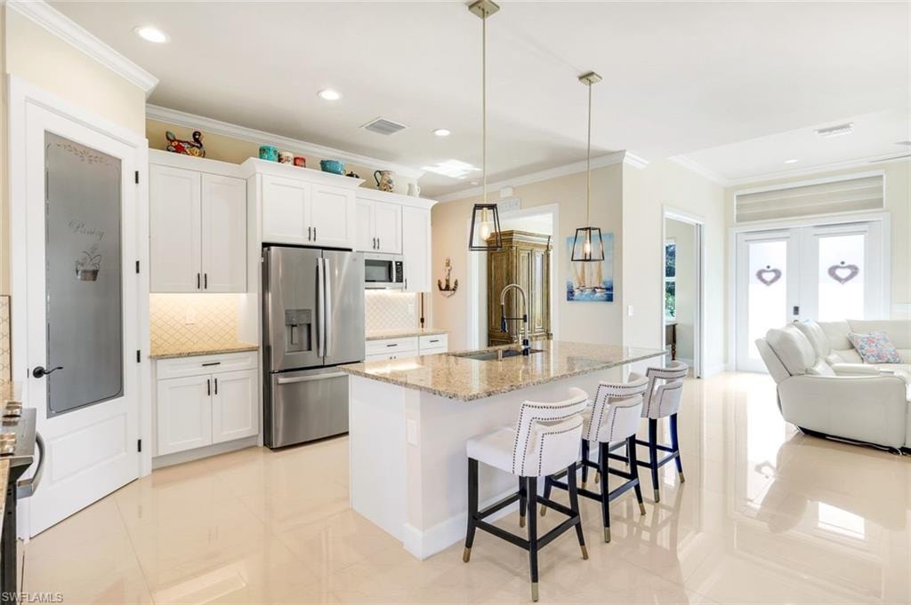 Kitchen featuring open floor plan, tasteful backsplash, a breakfast bar, stainless steel appliances, and crown molding