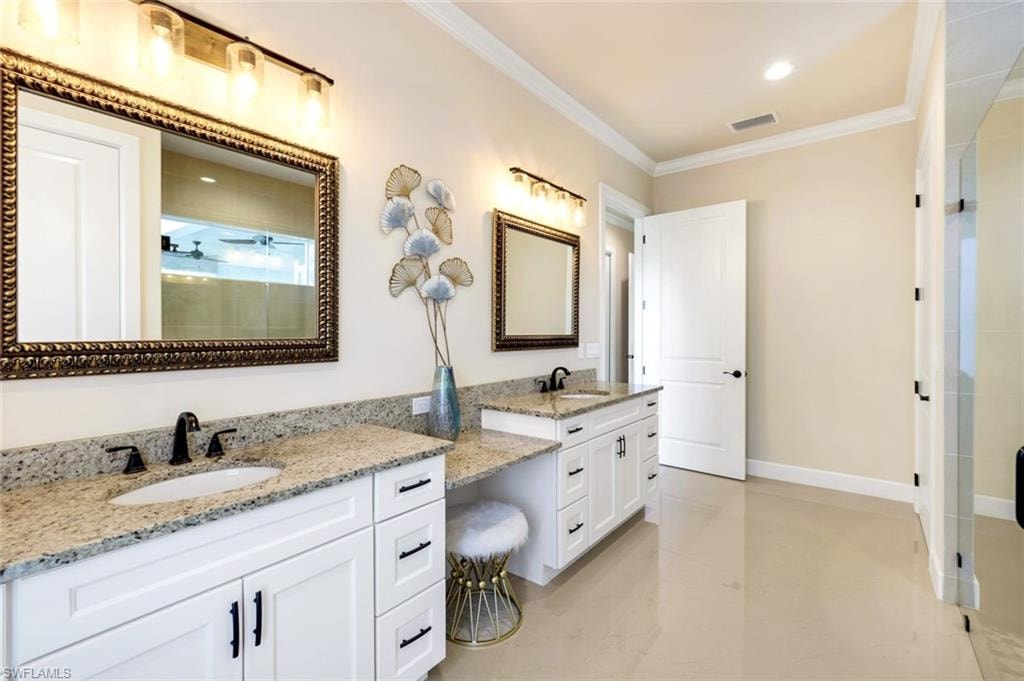 Full bath with a stall shower, crown molding, two vanities, double vanity, and recessed lighting