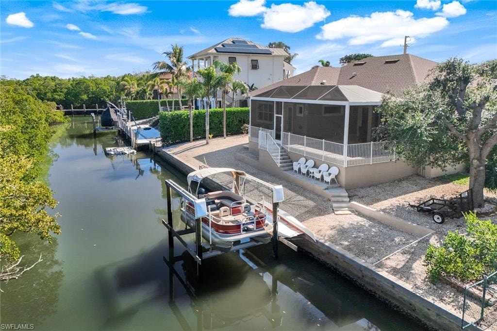 Dock area featuring boat lift, a water view, a sunroom, and a lanai