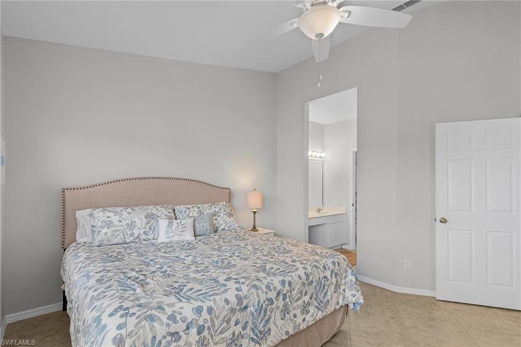 Bedroom featuring ensuite bath, a ceiling fan, and light tile patterned flooring