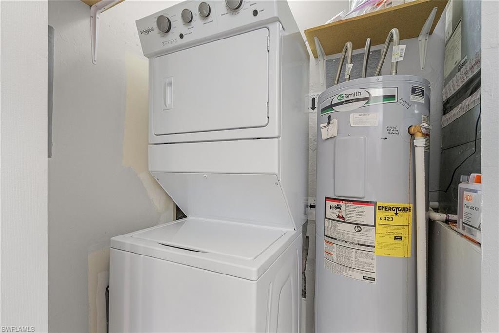Laundry room featuring water heater and stacked washing machine and dryer