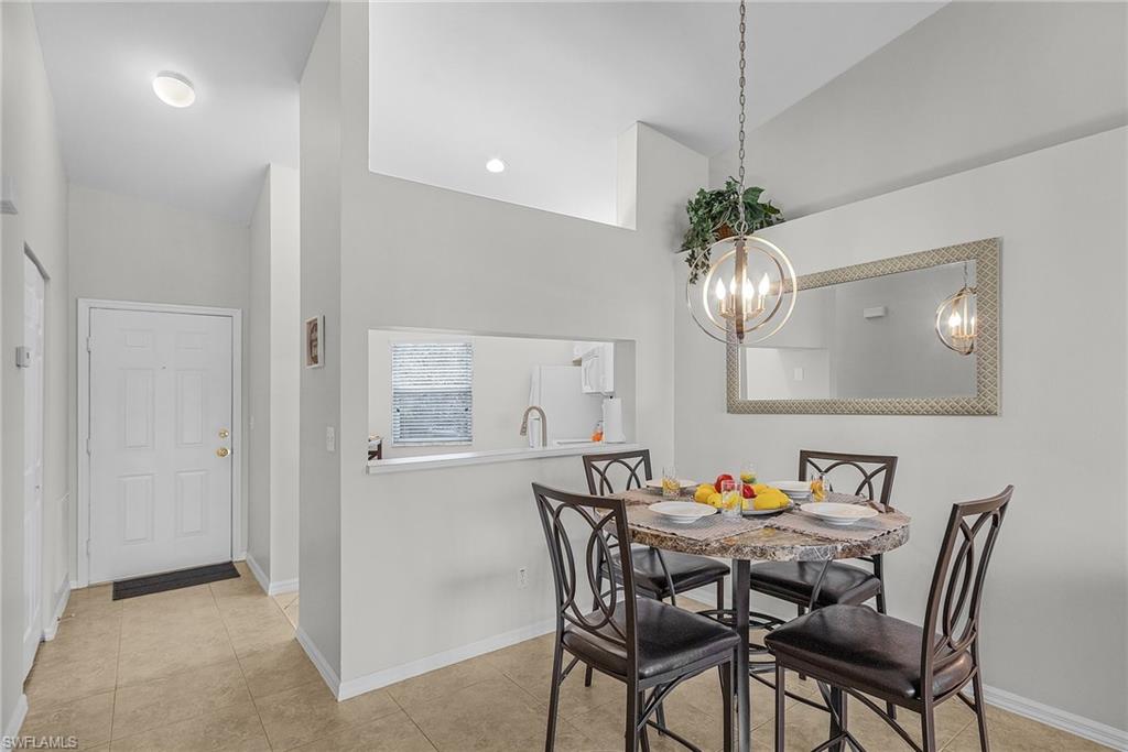 Dining room with light tile patterned floors, a chandelier, and a towering ceiling