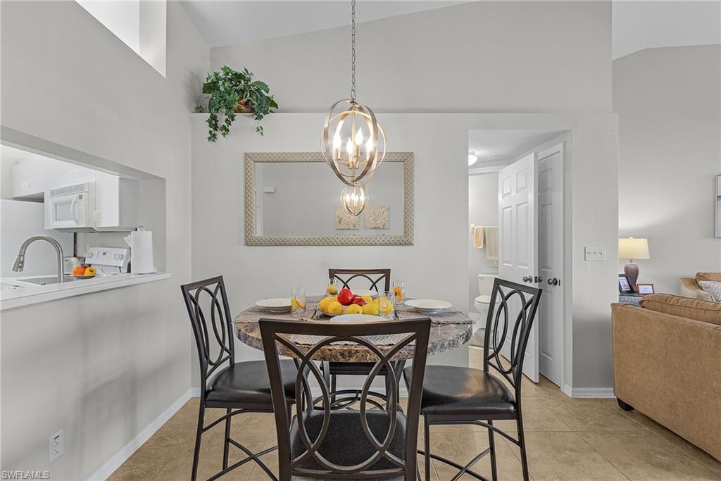 Dining space featuring light tile patterned floors, a chandelier, and high vaulted ceiling