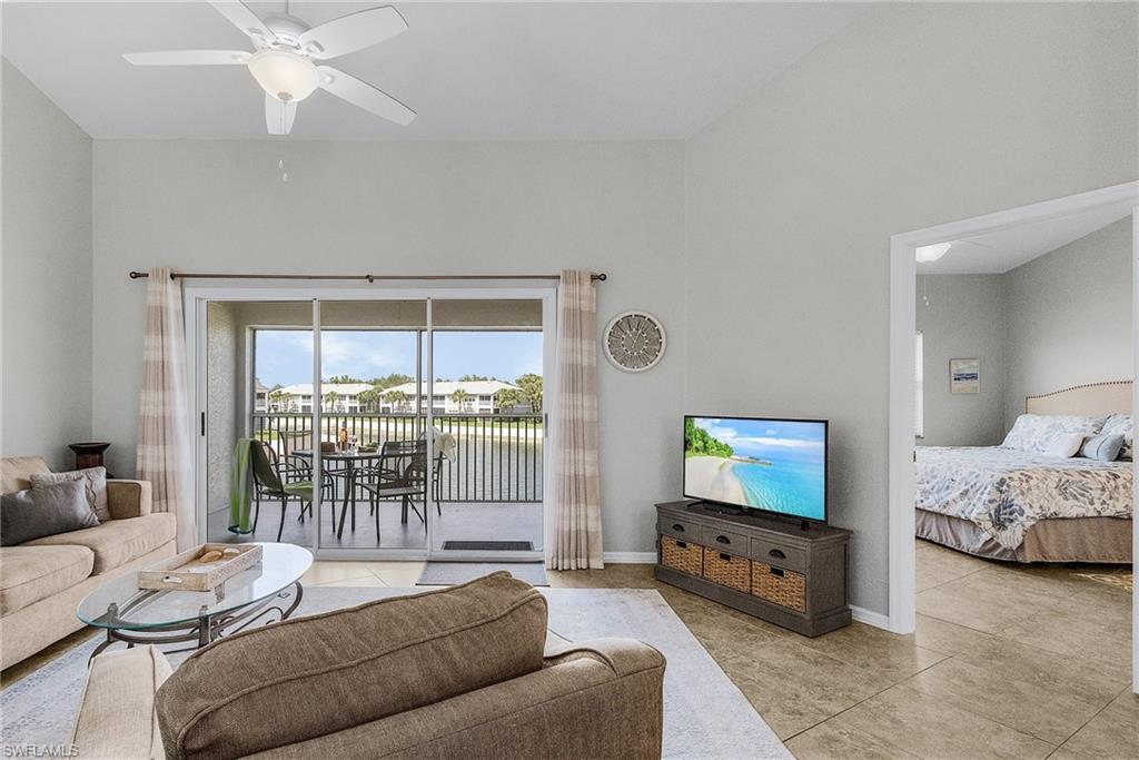 Tiled living area with ceiling fan and baseboards
