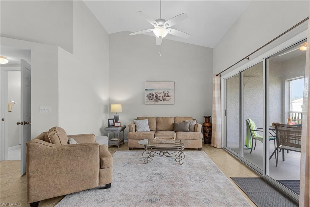 Living room featuring high vaulted ceiling, light tile patterned floors, and ceiling fan