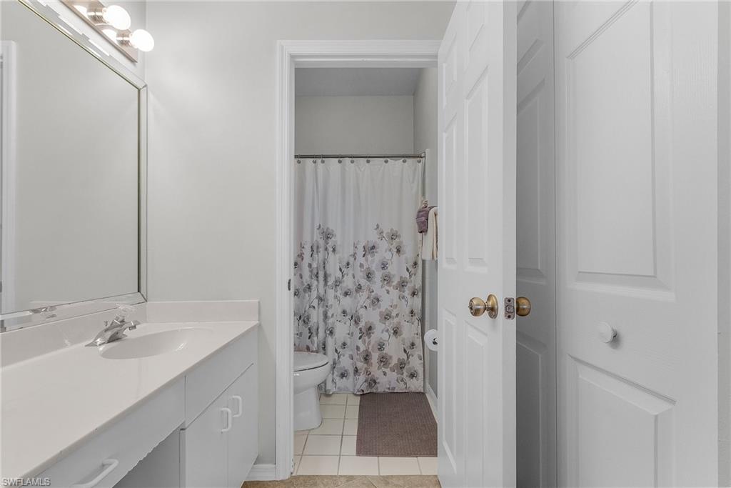 Full bathroom featuring light tile patterned floors, curtained shower, and vanity