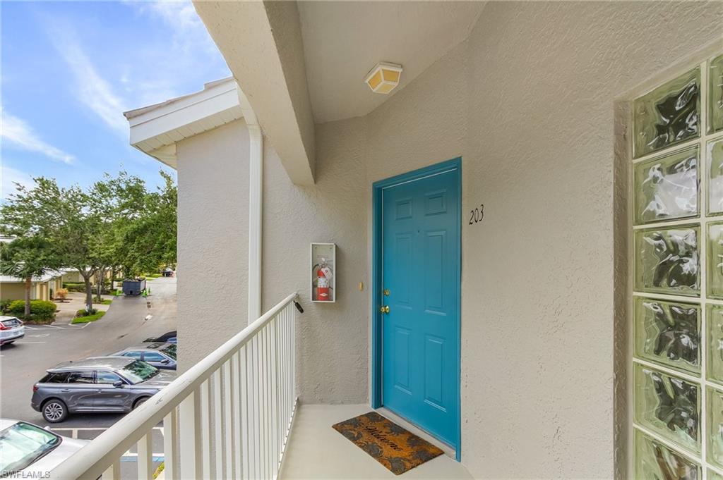 Property entrance with stucco siding and uncovered parking
