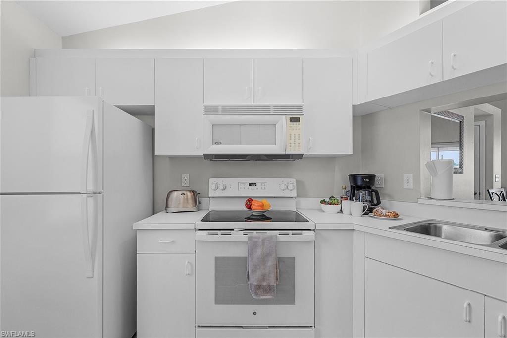 Kitchen featuring white appliances, light countertops, and white cabinets