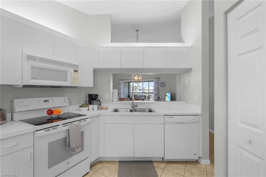 Kitchen with white appliances, light countertops, and white cabinets