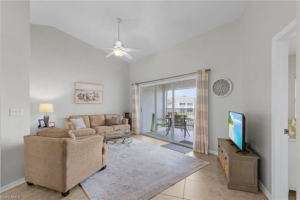 Living area featuring light tile patterned flooring, a ceiling fan, and high vaulted ceiling