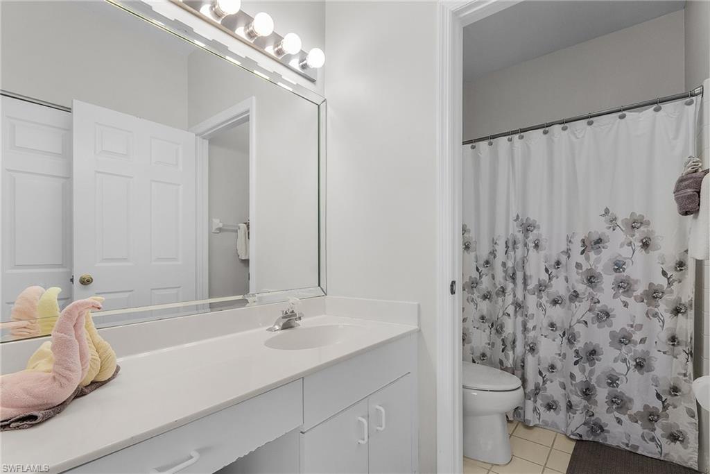 Full bath with light tile patterned floors, vanity, and curtained shower