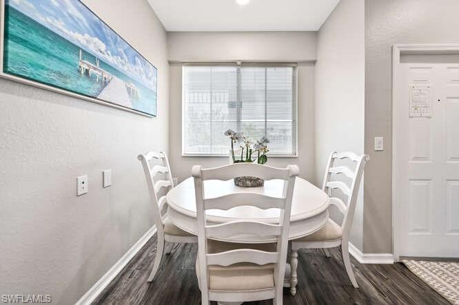 Dining area featuring dark wood-style flooring and a textured wall