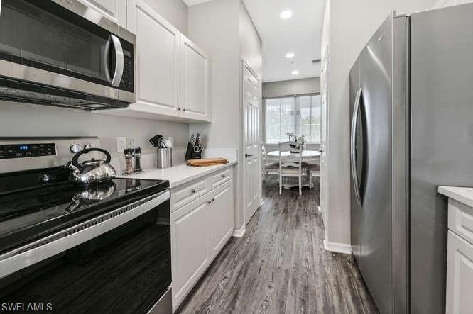 Kitchen featuring stainless steel appliances, white cabinets, dark wood-style floors, and recessed lighting
