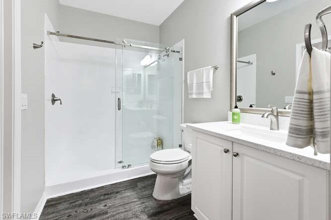 Full bathroom featuring a shower stall, vanity, and dark wood finished floors