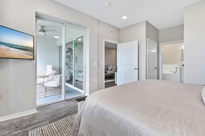 Bedroom with ensuite bath, dark wood finished floors, access to exterior, and recessed lighting