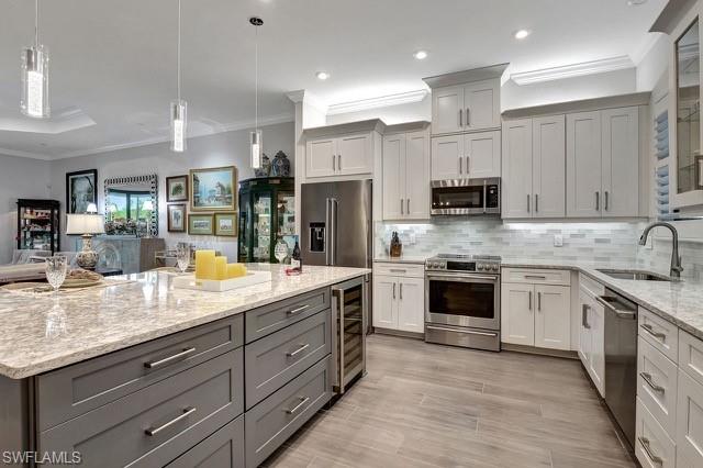 featuring wine cooler, decorative backsplash, Cambria Quartz  counters, upgraded stainless steel appliances, lower sized gray cabs with additional storage and pull outs