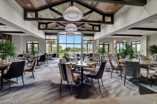 Featuring high vaulted ceiling, light colored carpet, and a wood ceiling with exposed beams overlooking grassy area
