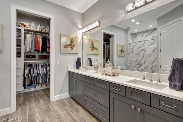 Featuring double sink vanity, quartz counter, and view of custom built walk-in closet