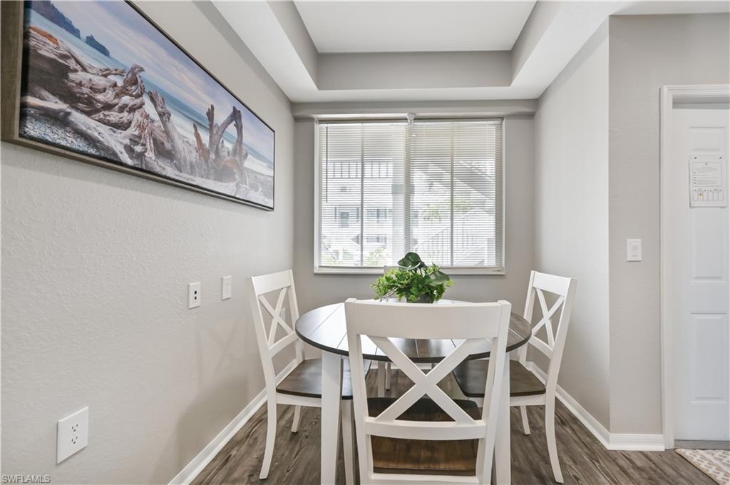 Dining space featuring dark wood-style flooring and a raised ceiling