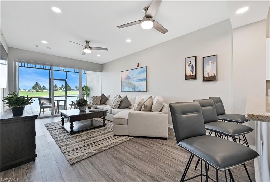 Living room with wood finished floors, a ceiling fan, recessed lighting, and a water view