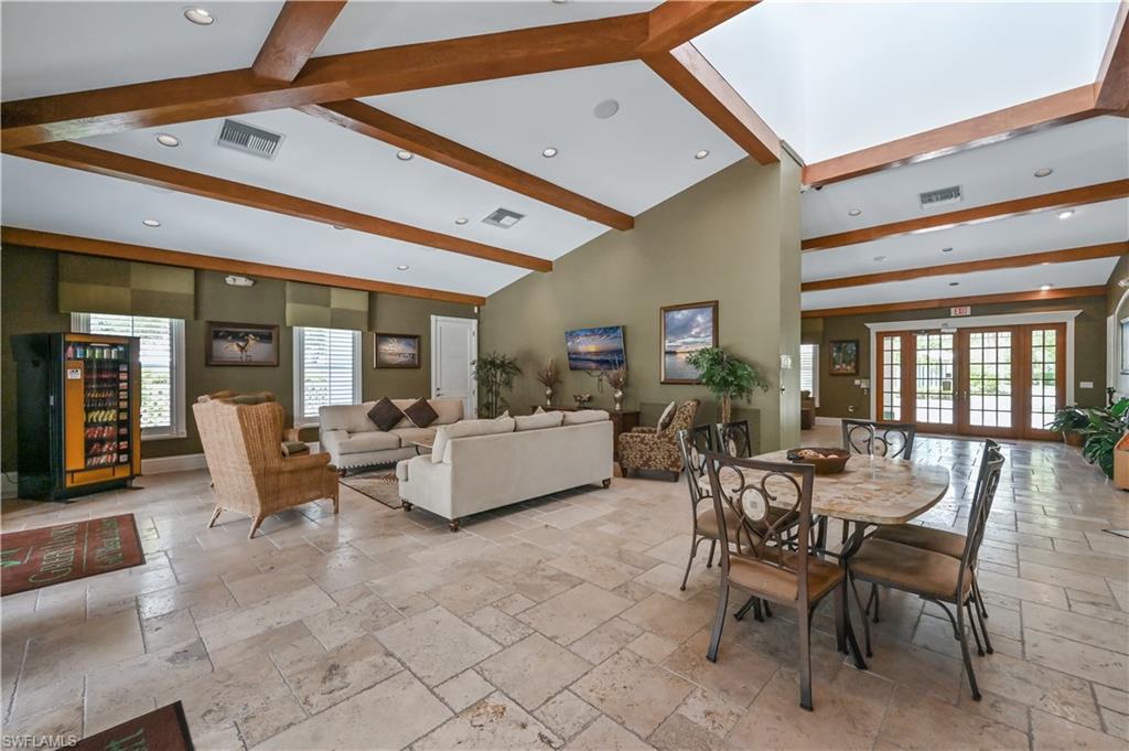 Dining room featuring stone tile flooring, healthy amount of natural light, beam ceiling, and high vaulted ceiling