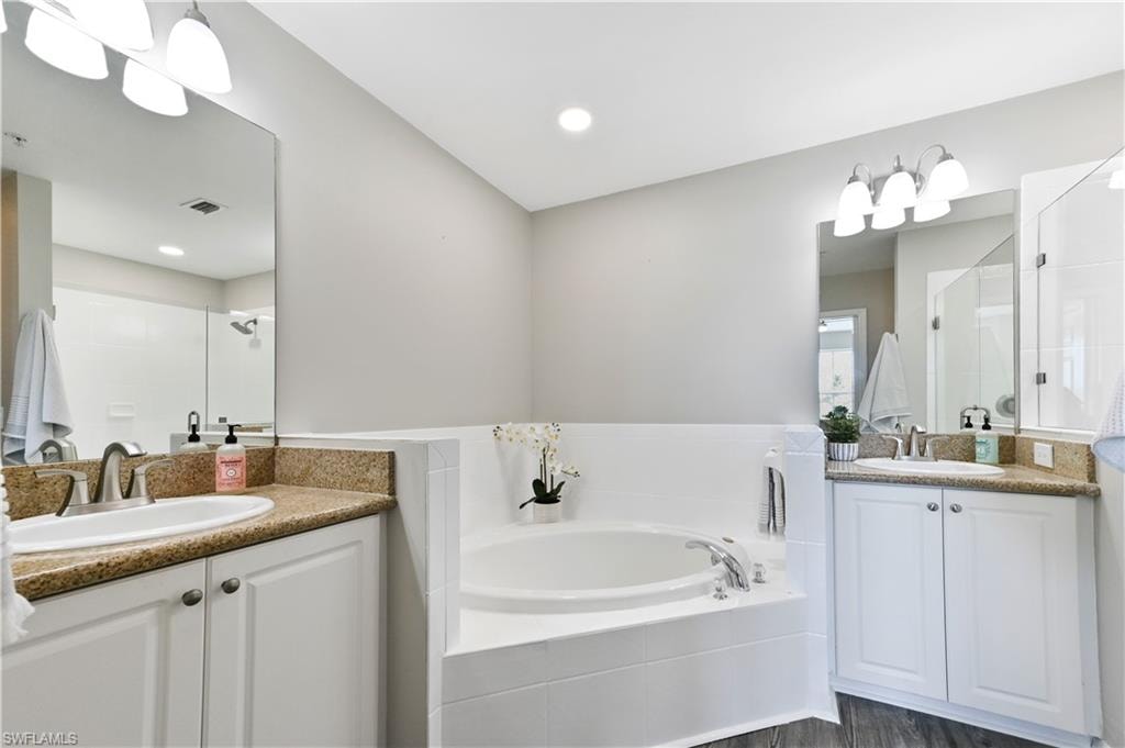 Full bath with two vanities, a garden tub, and a stall shower