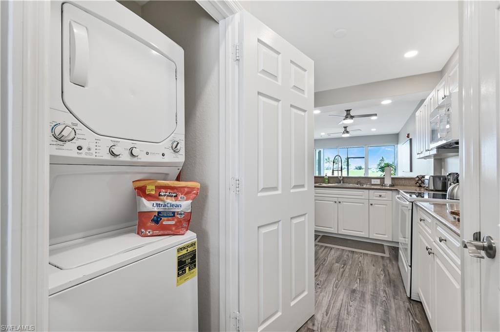Washroom featuring stacked washing machine and dryer, wood finished floors, a ceiling fan, and recessed lighting