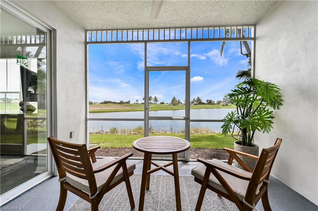 Sunroom with floor to ceiling windows, a water view, and a textured wall