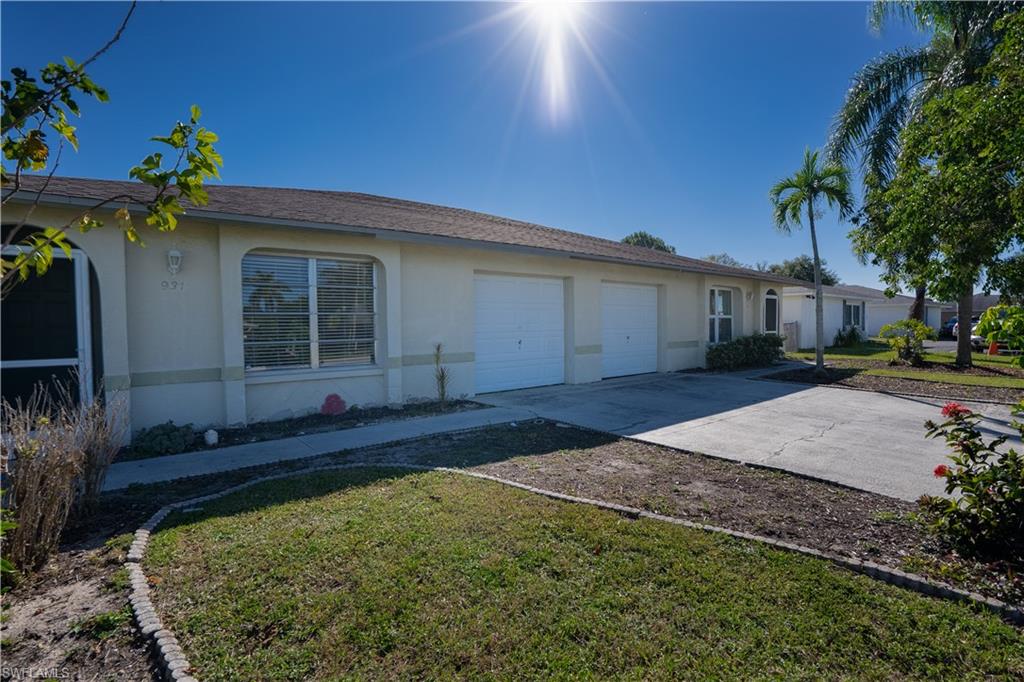 Ranch-style home with stucco siding, concrete driveway, an attached garage, and a front yard