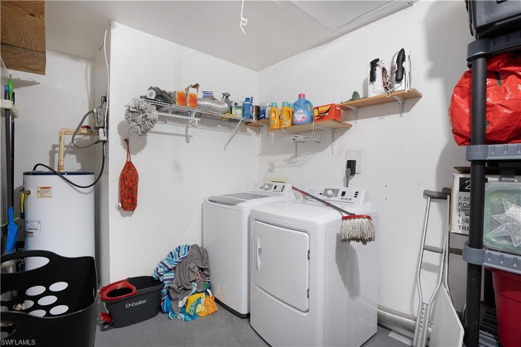 Laundry area with concrete flooring, washing machine and dryer, and water heater