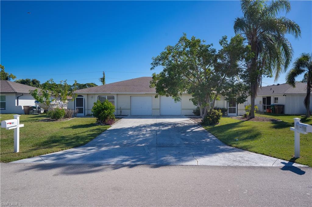 Ranch-style home with concrete driveway, a front lawn, and a garage