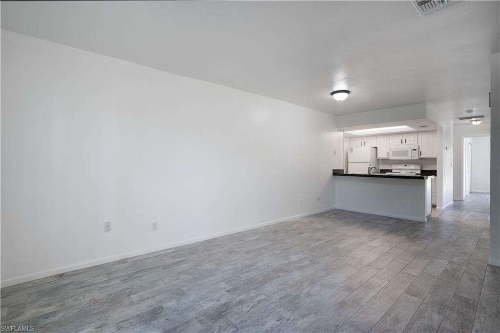 Unfurnished living room featuring light wood-style flooring and baseboards