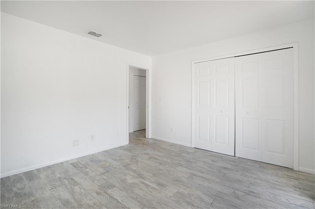 Unfurnished bedroom with wood finished floors and a closet