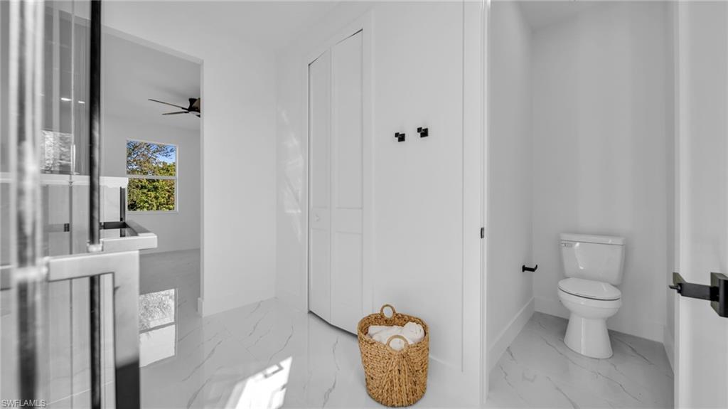 Bathroom featuring light marble finish flooring, a ceiling fan, and a closet