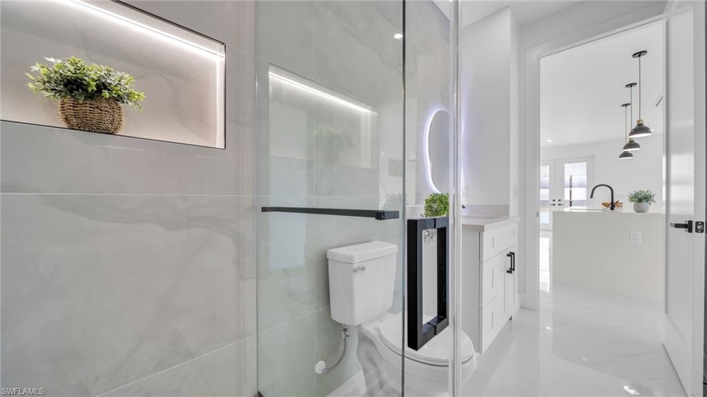 Bathroom with a stall shower, light marble finish flooring, and vanity