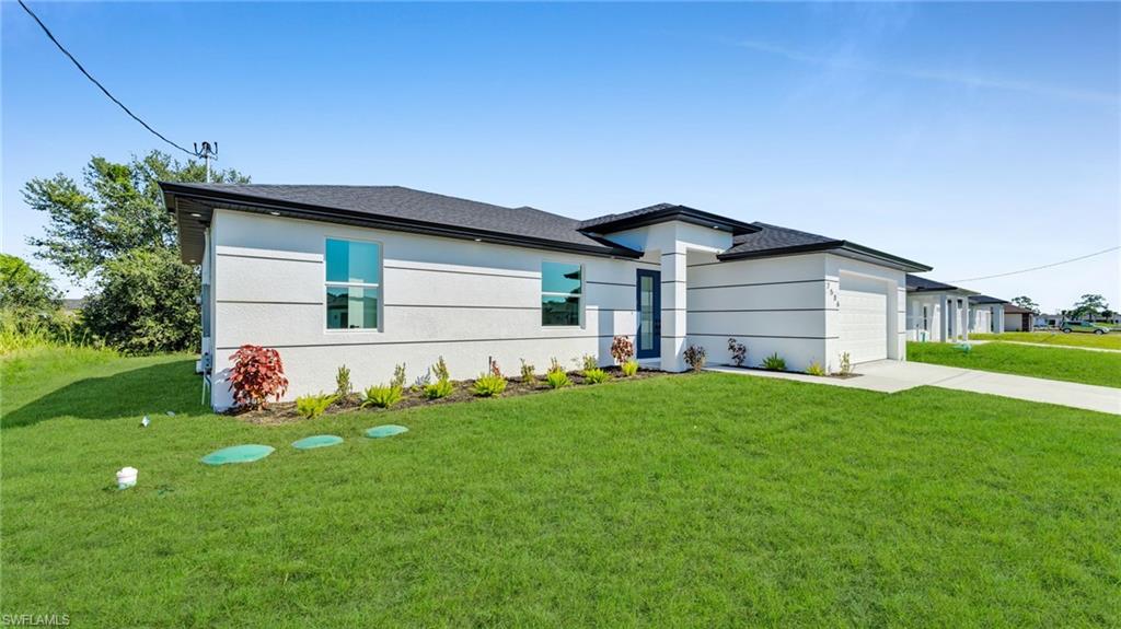 Prairie-style house with a front yard, concrete driveway, an attached garage, stucco siding, and roof with shingles