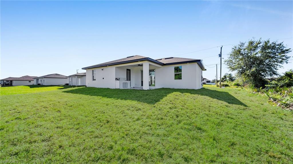 Back of property featuring stucco siding, a patio, a lawn, and ceiling fan