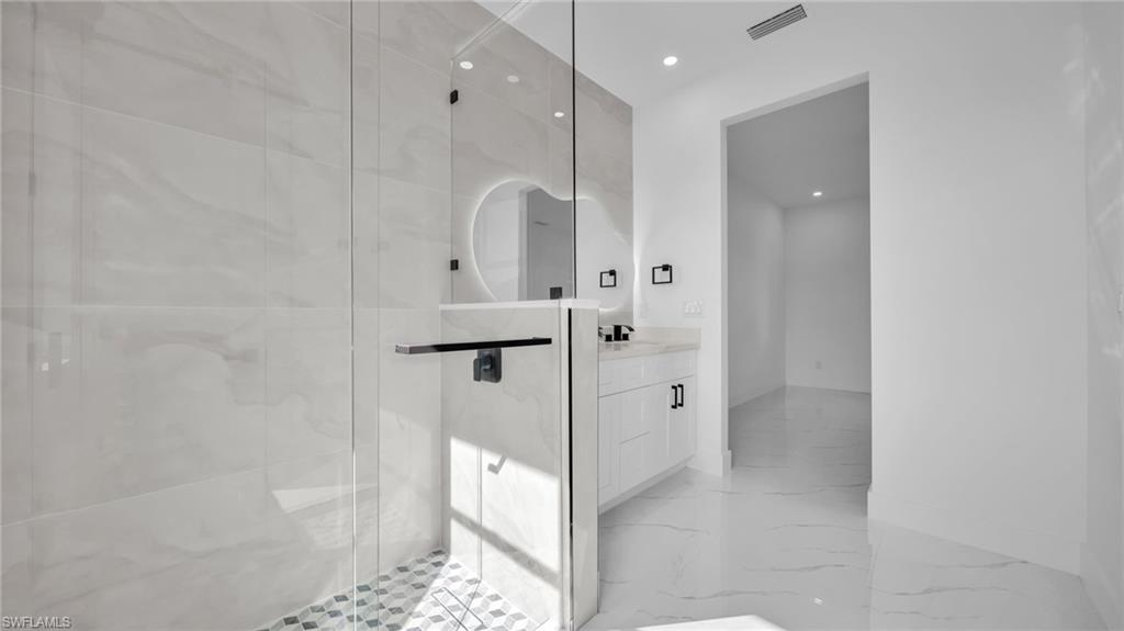 Full bath with vanity, recessed lighting, a marble finish shower, and light marble finish floors