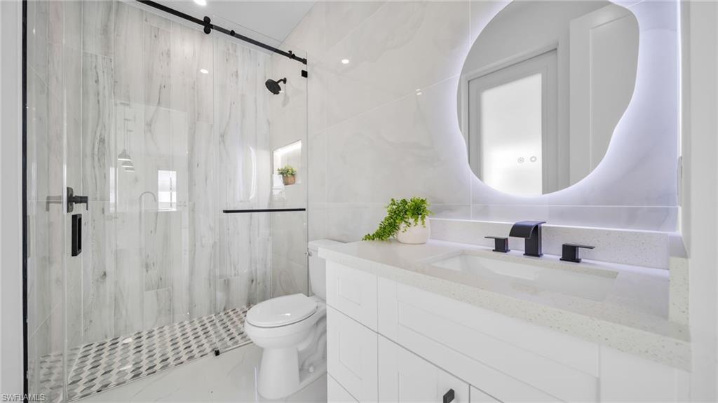 Bathroom featuring tile walls, vanity, and a marble finish shower