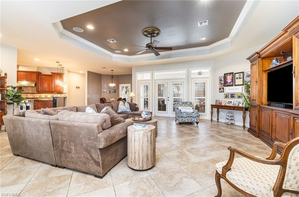 Living area featuring recessed lighting, ceiling fan, a raised ceiling, ornamental molding, and light tile patterned floors
