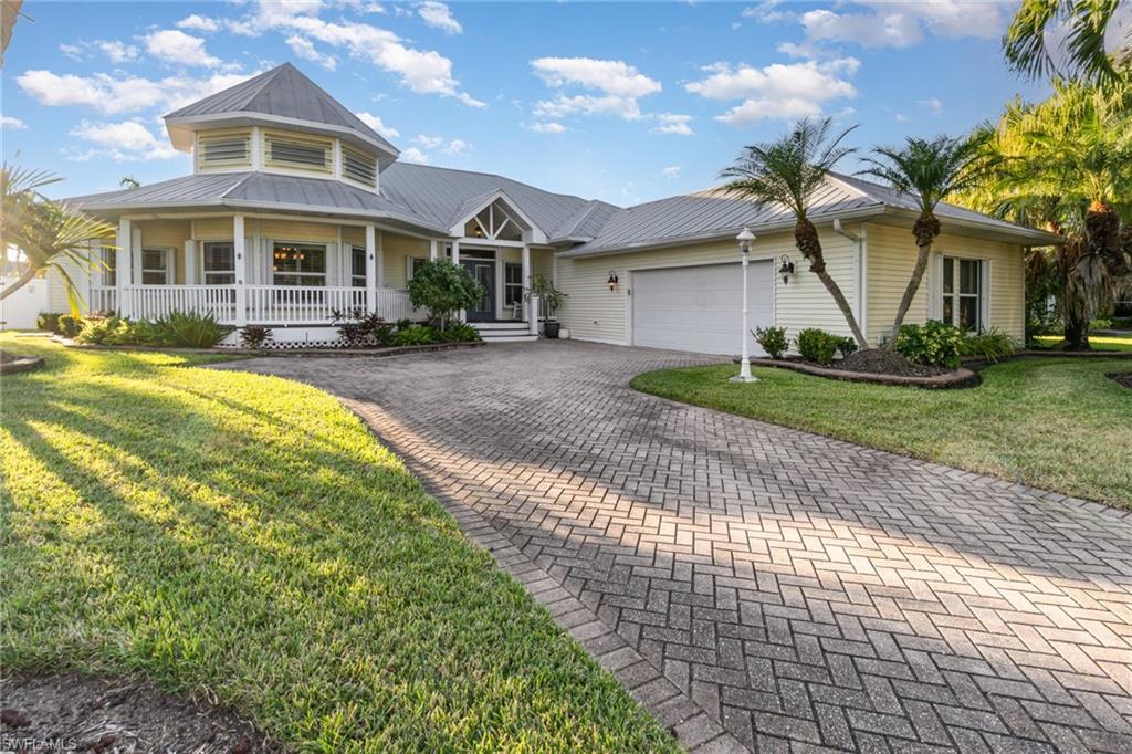 View of front of house featuring covered porch, a front lawn, decorative driveway, and a metal roof