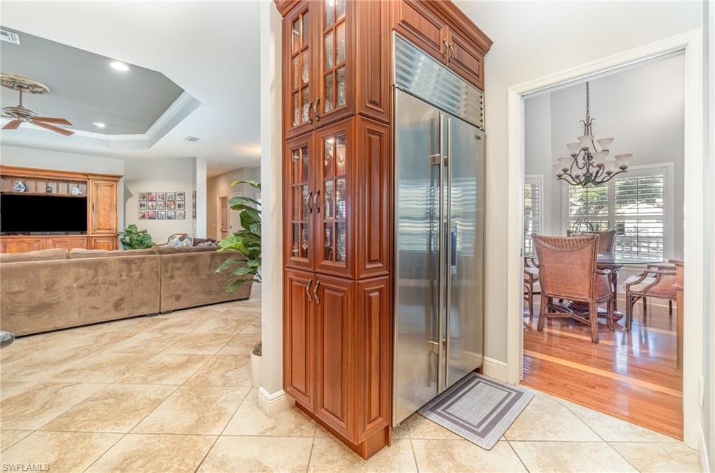 Kitchen with stainless steel built in fridge, a chandelier, light tile patterned floors, glass insert cabinets, and recessed lighting