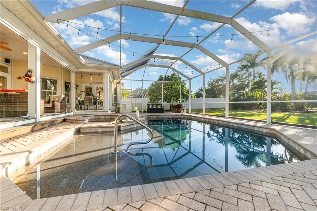 View of swimming pool with glass enclosure, a ceiling fan, a sunroom, a patio area, and a pool with connected hot tub