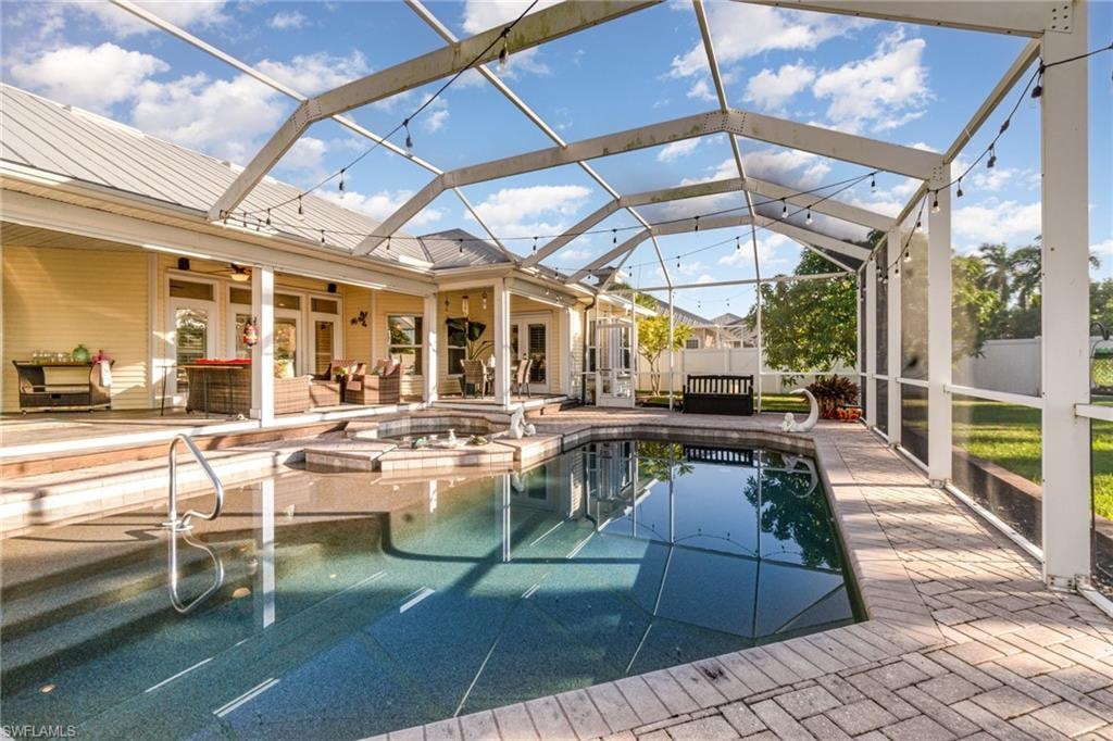 View of pool with a lanai, outdoor lounge area, a sunroom, and a patio area