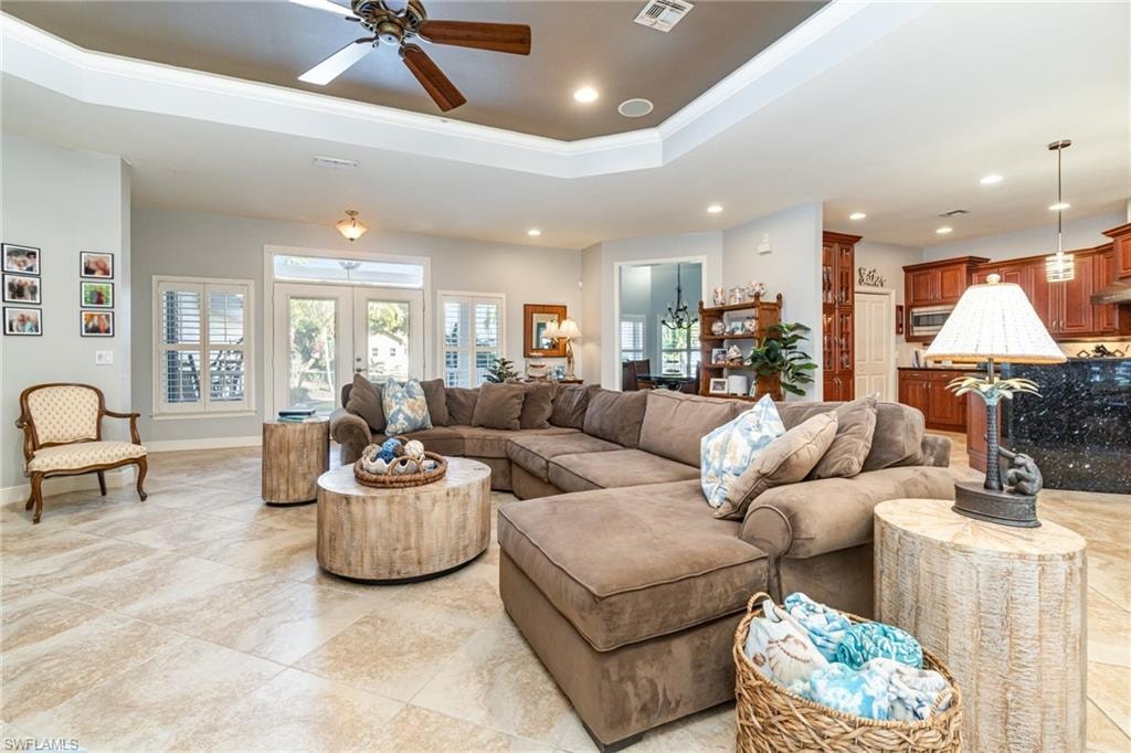 Living area with a tray ceiling, a ceiling fan, recessed lighting, and ornamental molding