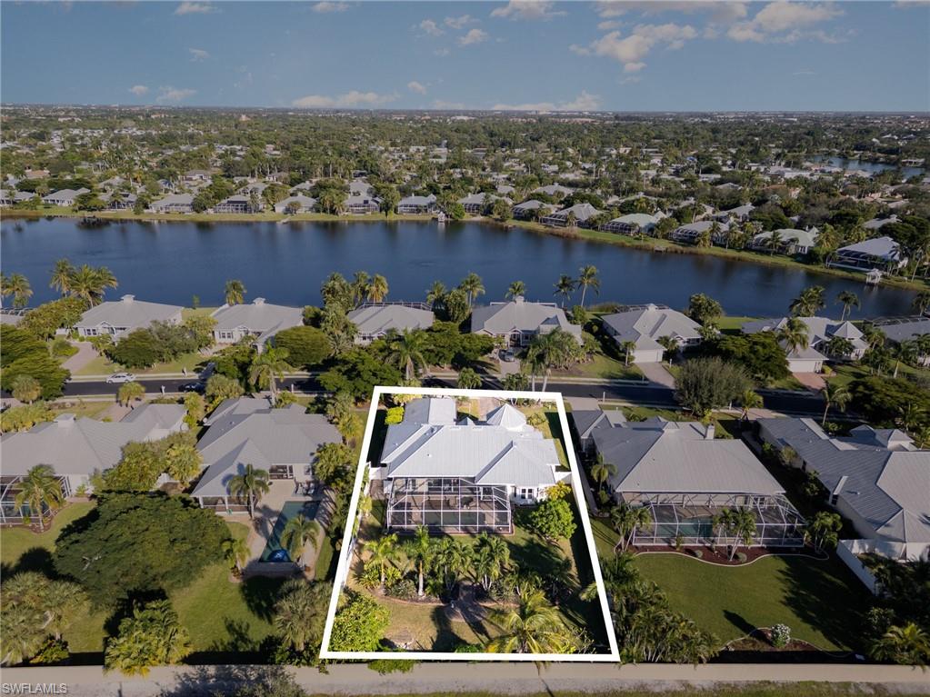 Aerial view of residential area with a large body of water and property boundaries highlighted