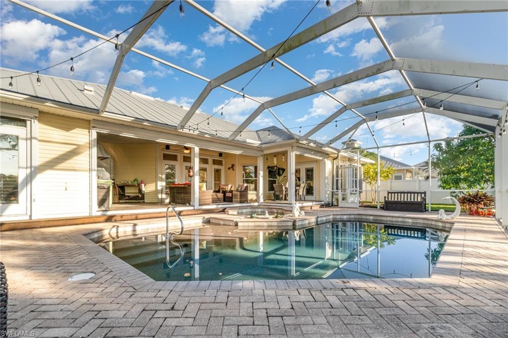 View of pool with an outdoor hangout area, a patio area, glass enclosure, a sunroom, and french doors