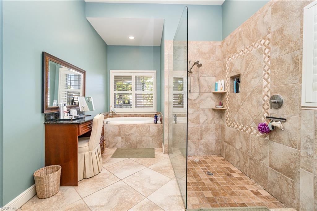Full bath with walk in shower, a bath, vanity, and light tile patterned floors