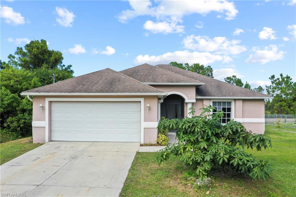 Single story home featuring stucco siding, driveway, an attached garage, roof with shingles, and a front lawn