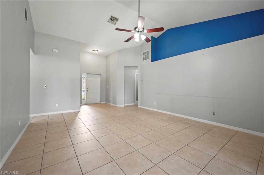 Unfurnished room with light tile patterned flooring, a ceiling fan, and high vaulted ceiling